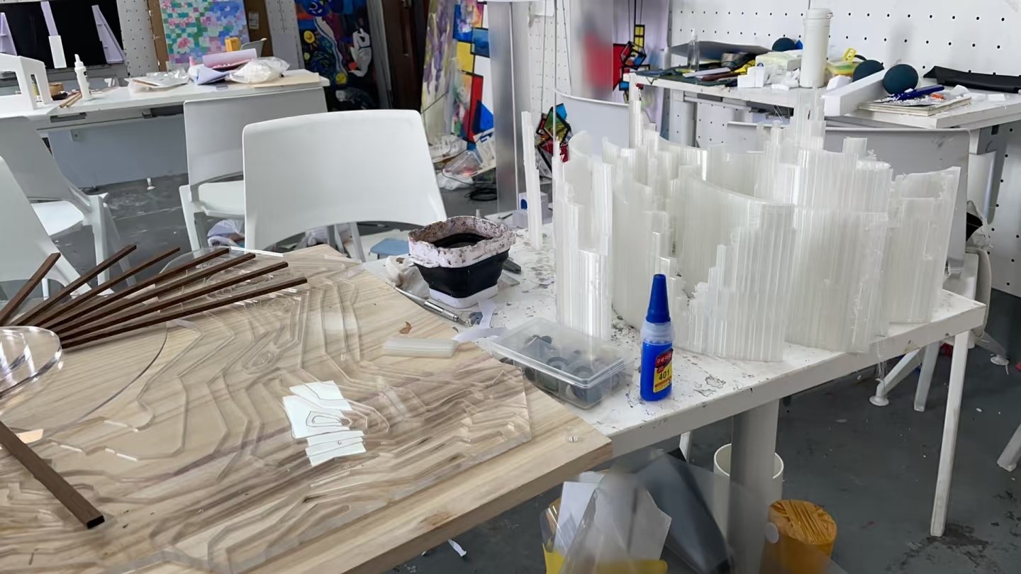 工作台上正在组装的透明地形层片、木质构件与工具