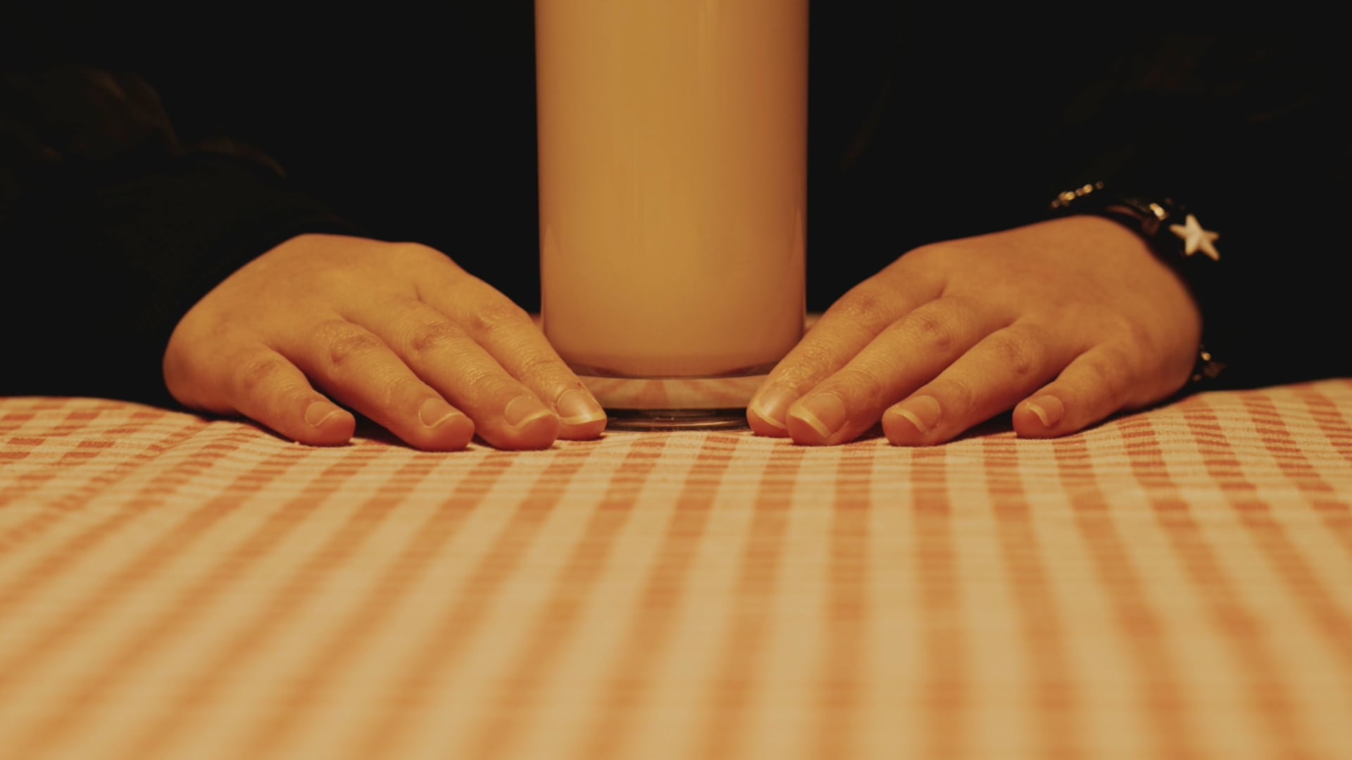 短片《白切鸡杀人案》中双手放在格纹桌布上，中央茶壶遮住人物面部