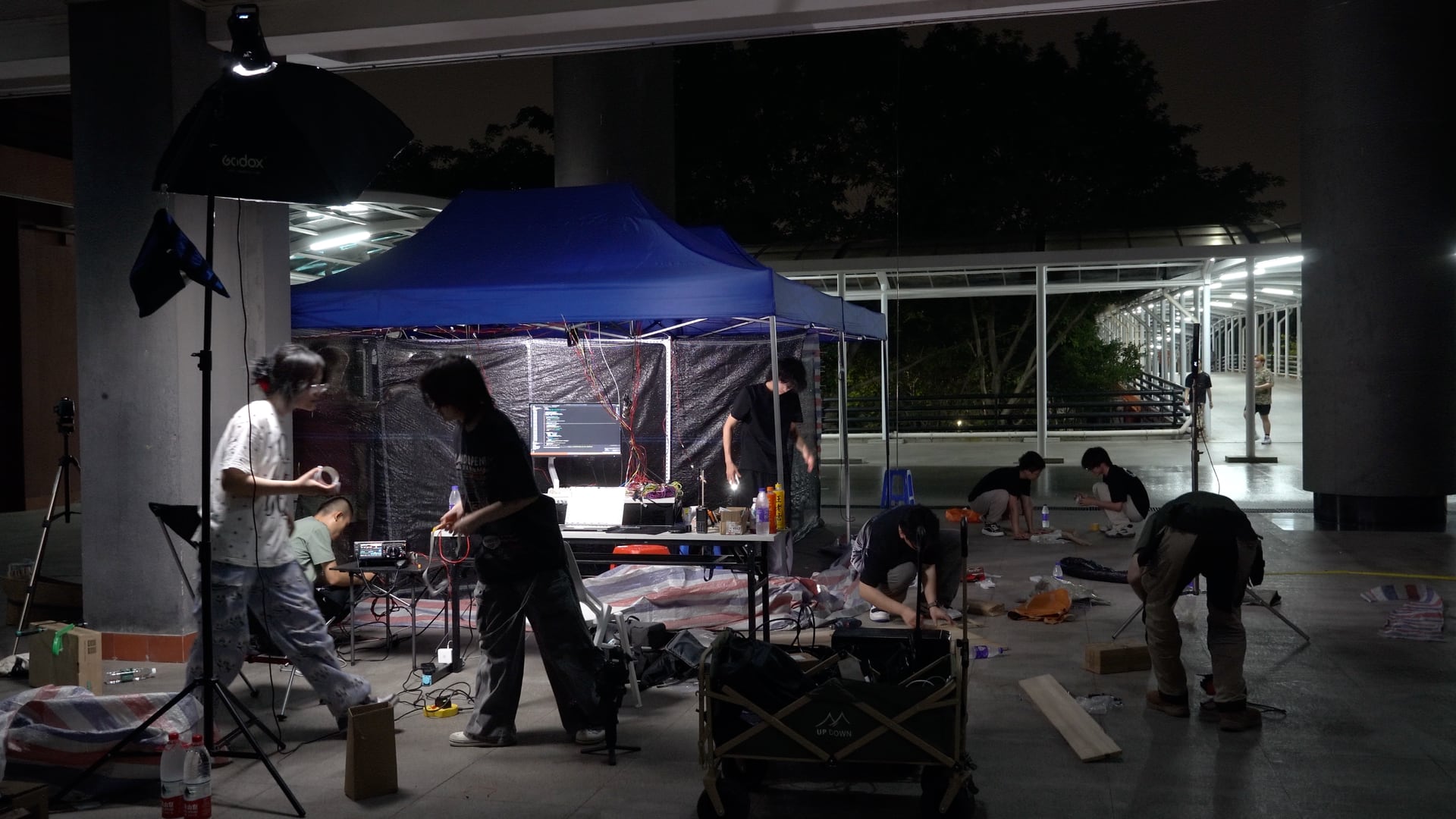 《人件—高仿驿站》夜间布展现场，团队围绕帐篷整理设备与材料