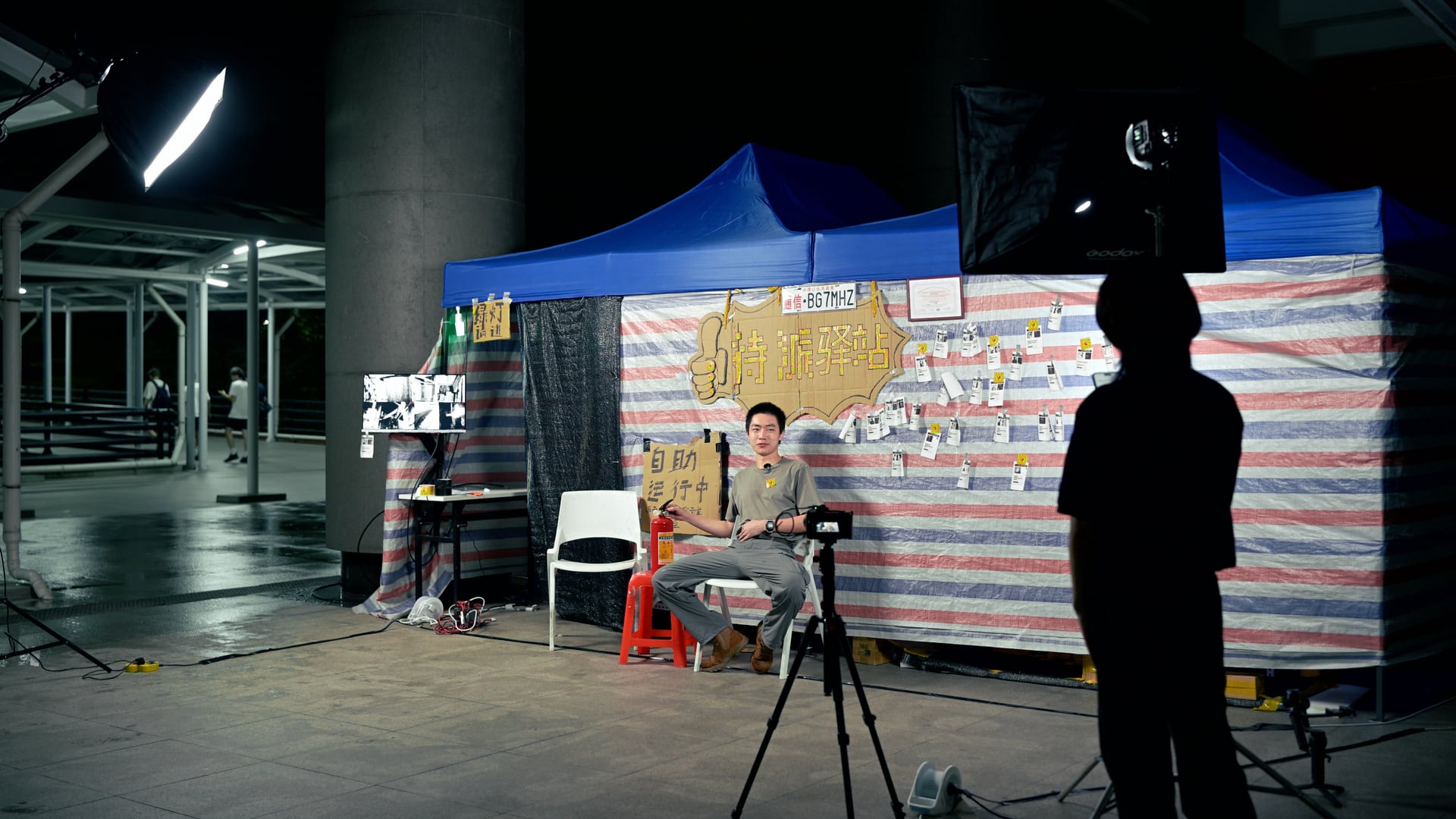 《人件—高仿驿站》夜间拍摄现场，灯光、相机与表演者围绕装置布置