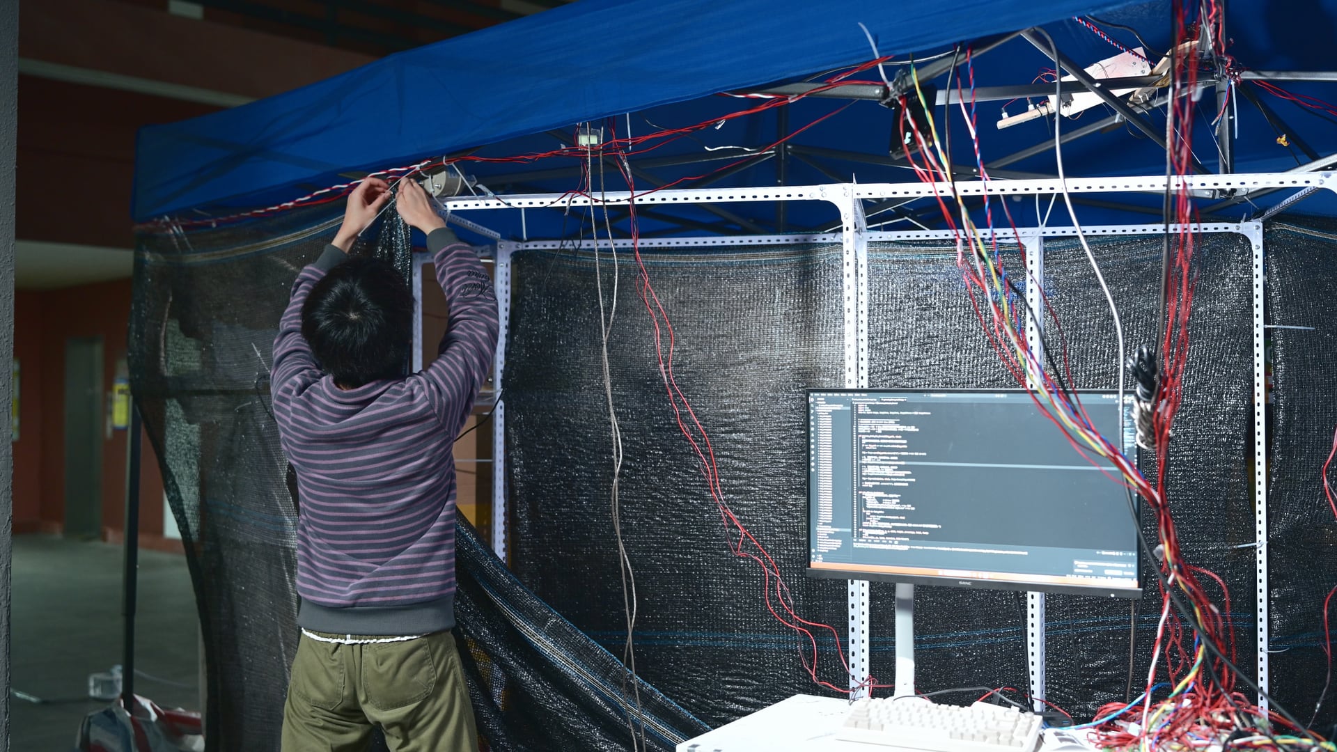 《人件—高仿驿站》搭建现场，团队在帐篷框架下整理多组控制线路